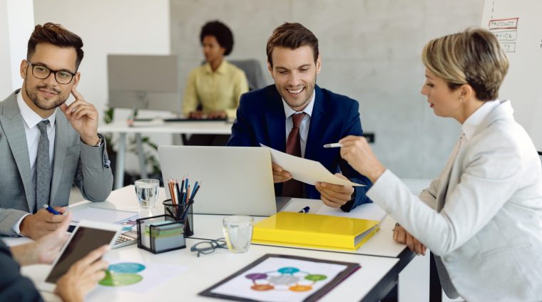 Happy colleagues cooperating while analyzing business reports on Happy businessman and his female colleague going through paperwork during a meeting in the office.